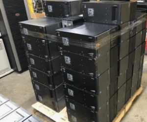 Stacked black server racks on a wooden pallet, showcasing organized hardware ready for installation or shipping in a tech environment.